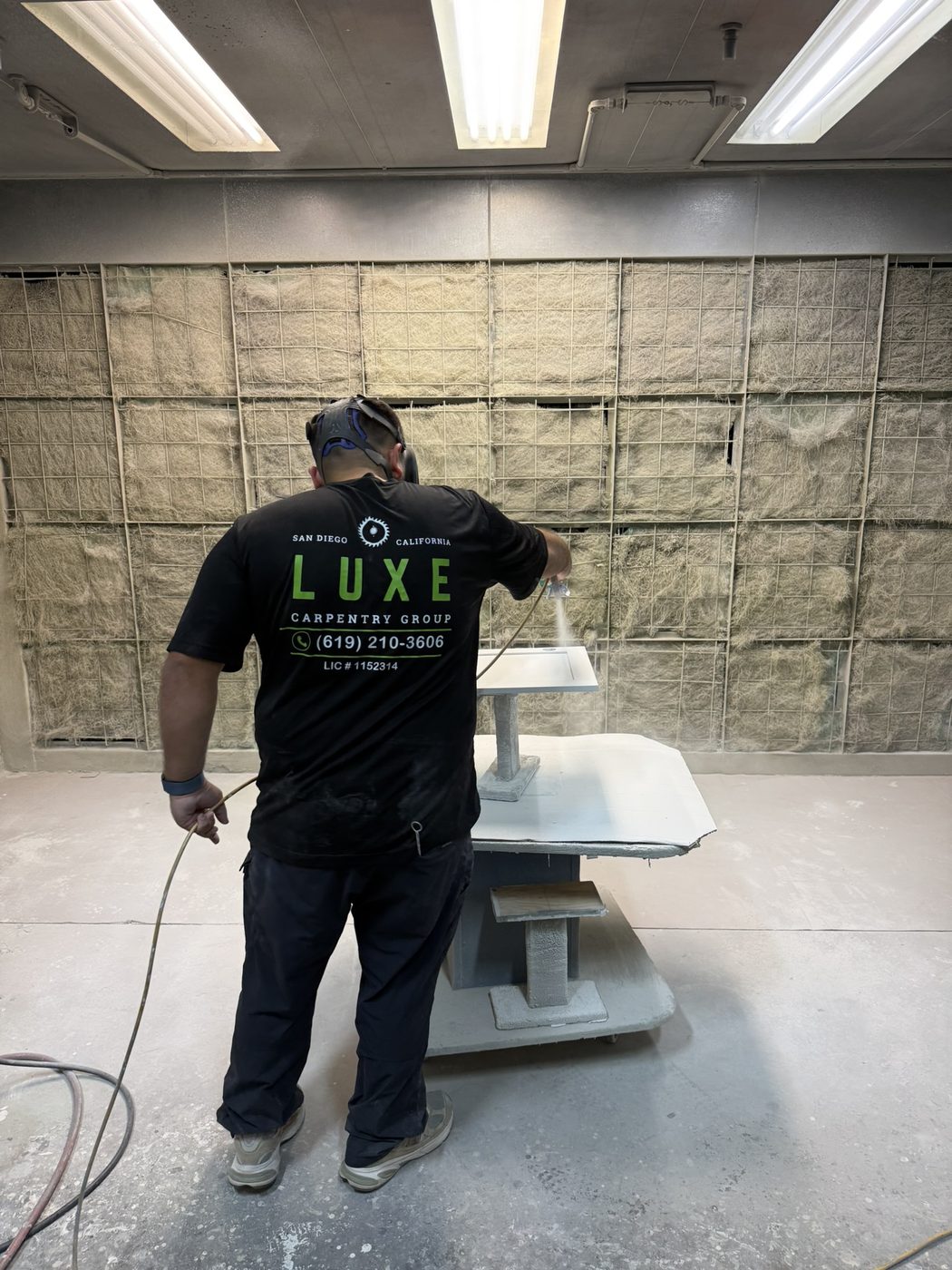 Luxe Carpentry Group finisher spraying in the enclosed booth with filtered exhaust wall — Luxe Carpentry Group, San Diego