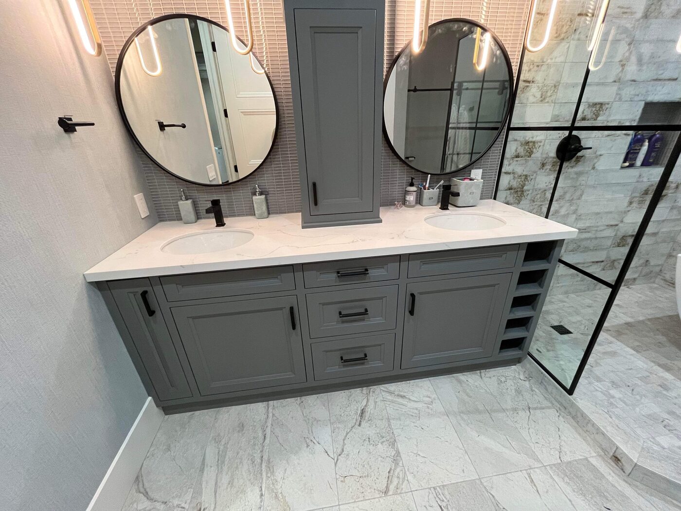 Grey double vanity with round mirrors and marble tile in a San Diego bathroom — Luxe Carpentry Group, San Diego